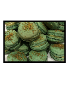 Photograph A colour image of a pile of green French Macarons, with numerous different fillings in each macaron, and a sprinkling of brown topping on each.